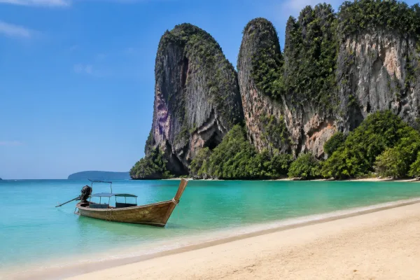 Pláž Railay v Krabi s vápencovými útesmi a loďou na tyrkysovej vode